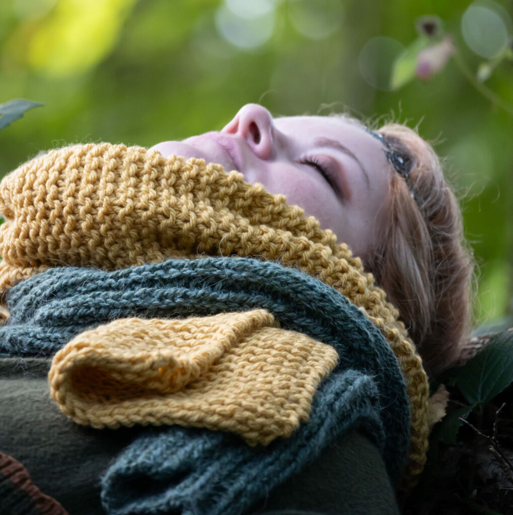 Femme au repos dans la forêt, enroulée dans des écharpes