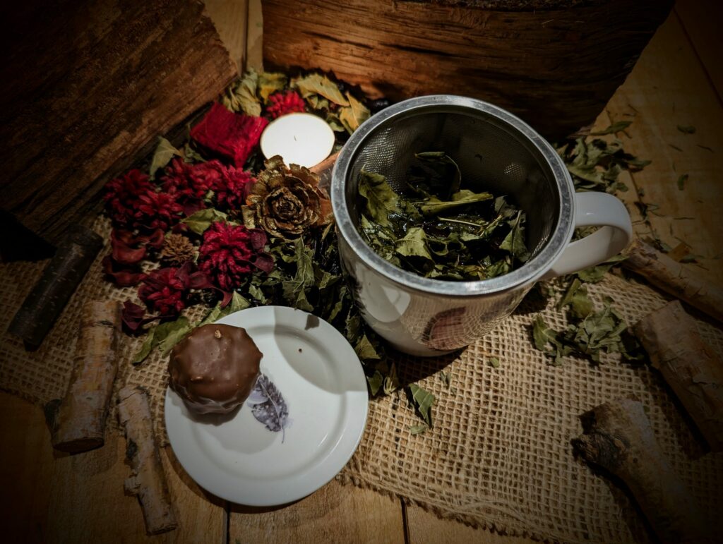 Tisane, chocolat dans une petite assiette, bougie et plantes séchées