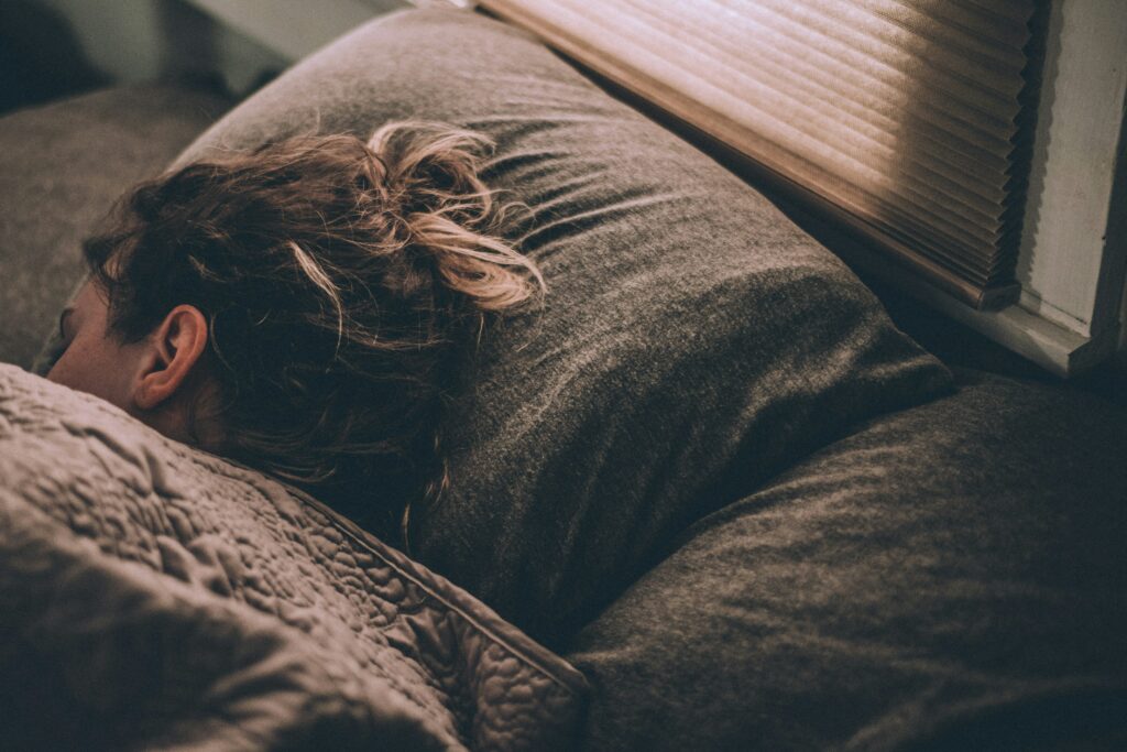 Une femme endormie dans son lit brun, au repos, apaisée