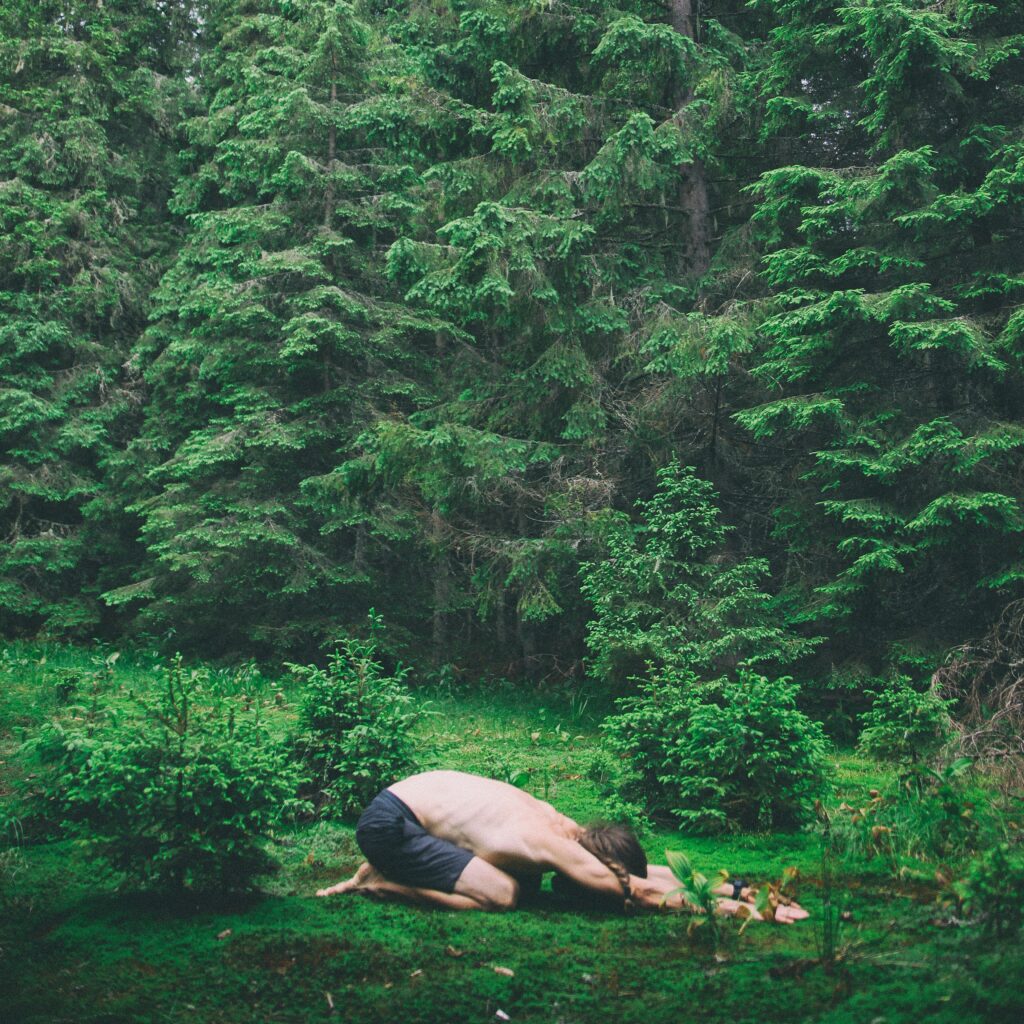 Un homme en posture de l'enfant dans une forêt, qui prend le temps de respirer