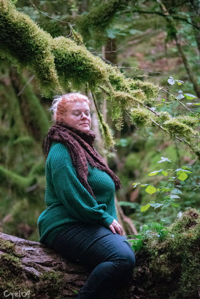 Une femme assise sur un tronc, dans une forêt, qui se détend