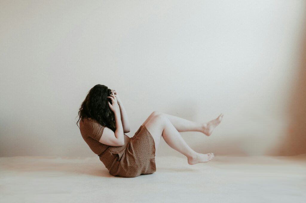 Une femme anxieuse qui est assise sur un sol blanc